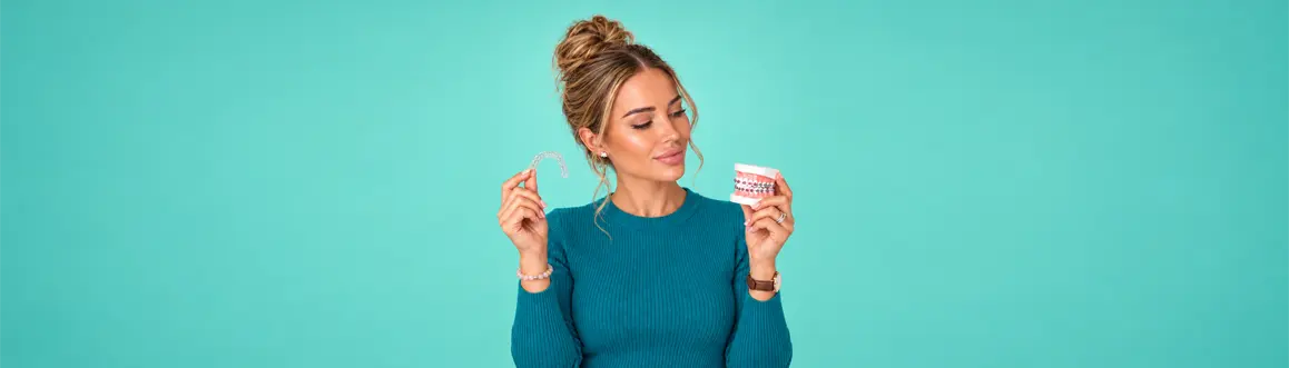 Dental hygienist holding a clear Invisalign aligner and a dental model — Airflow Guided Biofilm Therapy cleaning for patients with braces or Invisalign in Toronto